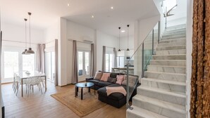 A spacious living area with a modern sofa, a dining table, and a staircase. - Villa Esperanza Canillas de Albaida by Ruralidays (Málaga)