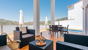 A terrace with wicker furniture, a table with chairs, and a pool in the background. - Villa Esperanza Canillas de Albaida by Ruralidays (Málaga)