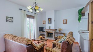 A living room with a fireplace, striped sofas, a television, and a chandelier. - Casas Villanueva - Casa Familiar Conil de la Frontera by Ruralidays (Cádiz)