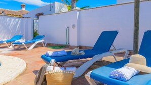 A poolside area with blue lounge chairs, a small pool, and a white wall. - Casas Villanueva - Casa Familiar Conil de la Frontera by Ruralidays (Cádiz)