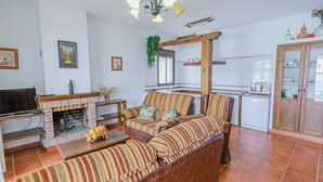 A living room with a fireplace, striped sofa, and a television. - Casas Villanueva - Casa Familiar Conil de la Frontera by Ruralidays (Cádiz)