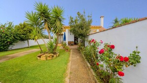 A garden with a pathway leading to a building with a tiled roof and a chimney. - Casas Villanueva - Casa Familiar Conil de la Frontera by Ruralidays (Cádiz)