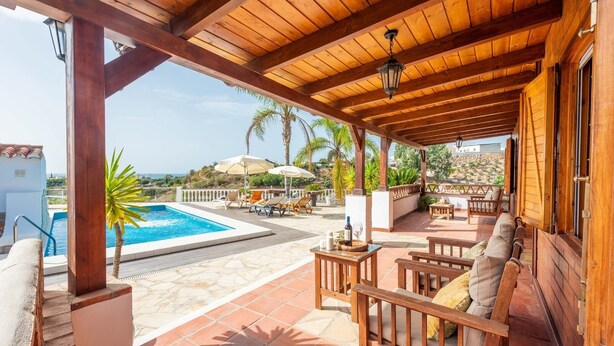 Un espace extérieur abrité comprenant une piscine, des chaises longues et une pergola en bois.