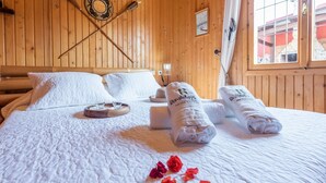 Un lit bien fait, avec du linge de lit blanc, deux serviettes enroulées et un plateau avec des verres et une bougie.