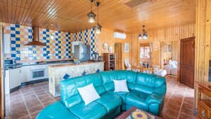 Un intérieur de chalet chaleureux comprenant une cuisine, un coin repas et un grand canapé en cuir turquoise.