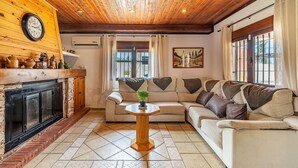 A cozy living room with a fireplace, a sofa, a coffee table, and a clock on the wall.
