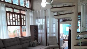 Un salón amplio con un sofá seccional gris grande, una mesita redonda y una escalera de caracol.