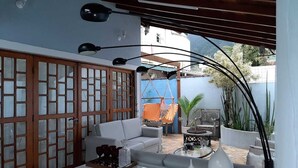 Un espacio al aire libre techado con un sofá blanco, una mesita de centro y una hamaca.