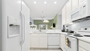 Une cuisine moderne avec des meubles blancs, un lave-vaisselle encastré, une cuisinière et un four à micro-ondes.