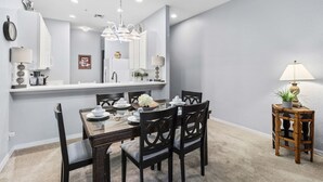 Un coin repas avec une table en verre, des chaises noires, des murs blancs et un miroir au-dessus de la table.