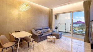 Una sala moderna con un sofá, una mesa de comedor y sillas. Hay un balcón con mobiliario exterior.