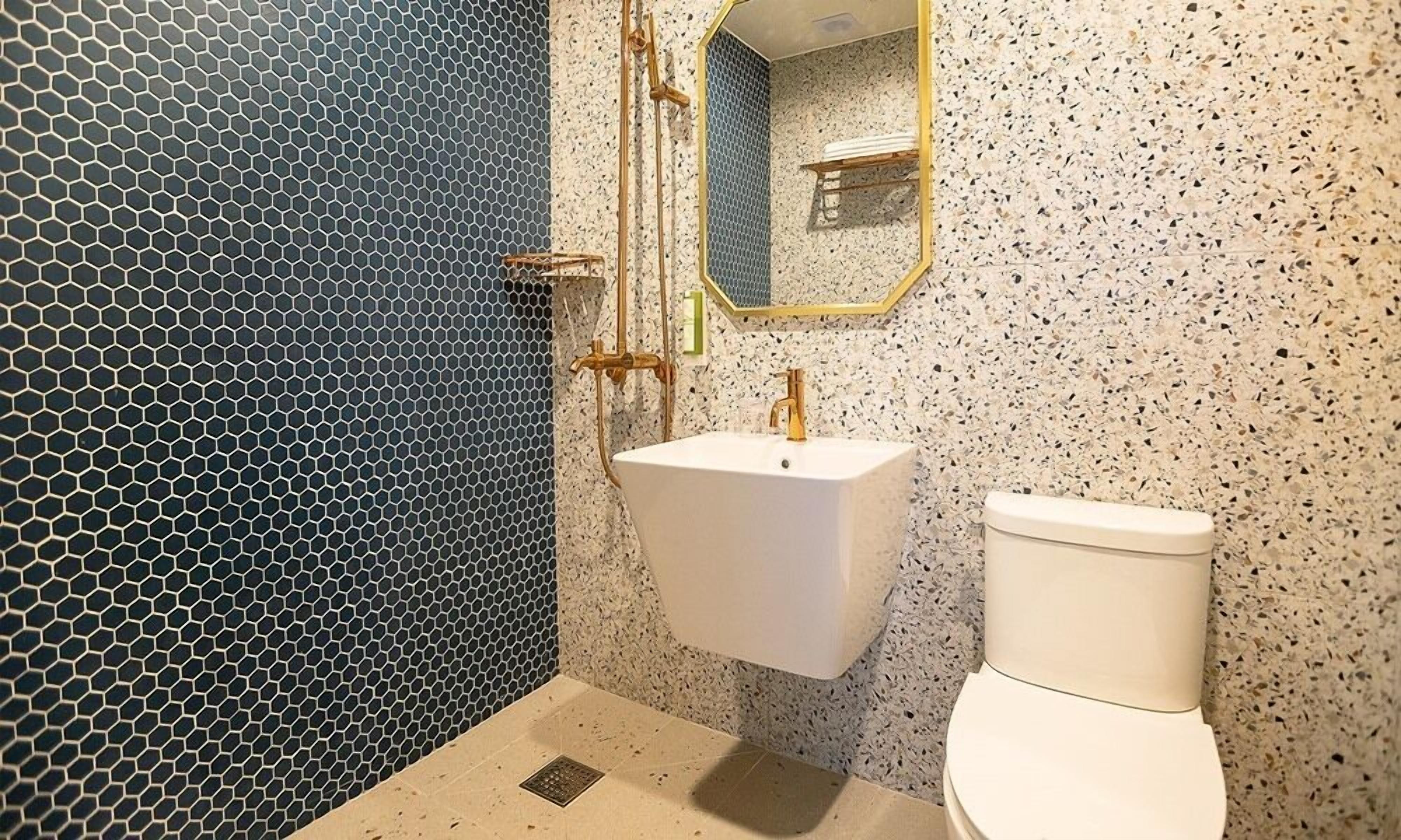 A bathroom with a hexagonal patterned wall, a white sink, and a toilet.