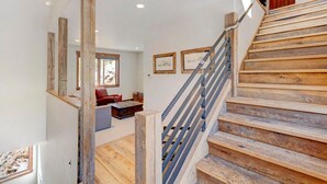 A wooden staircase with a metal handrail, a red leather sofa, and framed artwork on the walls.