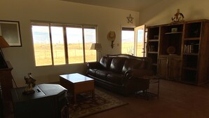 A living room with a leather sofa, a wooden coffee table, a lamp, and a star decoration on the wall. - Sunset Ride Ranch /Foreman's house (Elgin)