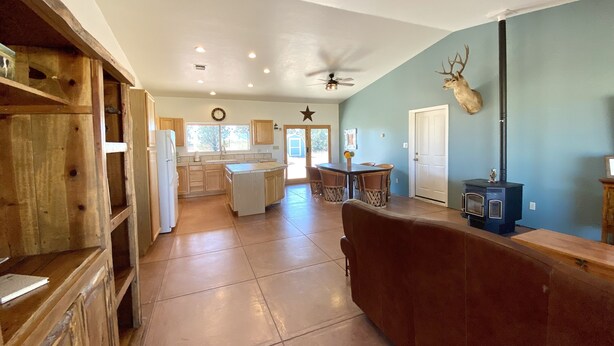 A spacious kitchen with wooden cabinets, a central island, and a dining area with chairs. - Sunset Ride Ranch /Foreman's house (Elgin)