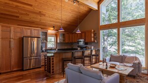 A modern kitchen with wooden cabinets, stainless steel appliances, and a large island with bar stools. - JHRL - Lookout Lodge, short walk to base of Jackson Hole Mountain Resort (Teton Village)