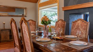 A dining room with a wooden table set for four, surrounded by ornate chairs, a vase with flowers, and a wine bottle. - JHRL - Lookout Lodge, short walk to base of Jackson Hole Mountain Resort (Teton Village)