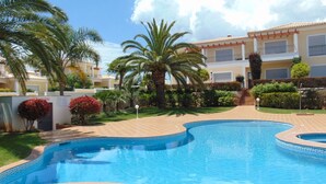 A swimming pool surrounded by palm trees and a building with balconies.