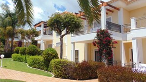 A hotel with multiple balconies, lush greenery, and a well-maintained garden.