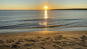A beach with footprints in the sand and a sunset over the water. - Sunset Villa Across the Street from Beach & Walk to Pool / Golf
 (Johns Island)