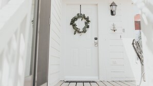 A white house with a front door, a wreath, and a lantern on the wall. - Sunset Villa Across the Street from Beach & Walk to Pool / Golf
 (Johns Island)