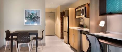 A modern kitchen with a dining area, including a table and chairs, a microwave, and a refrigerator.