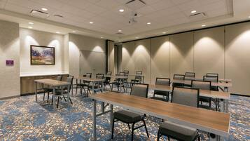 A conference room with a long table, chairs, a projector screen, and a carpeted floor.