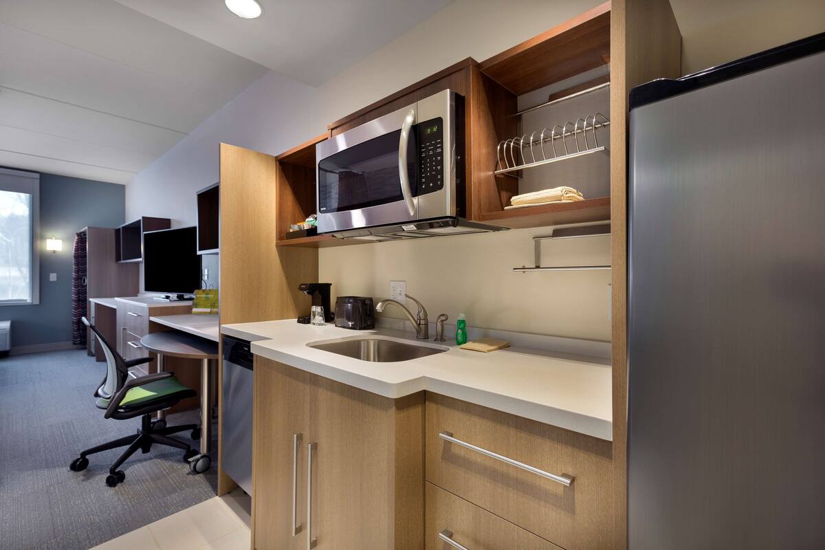 A modern kitchen with a built-in microwave, stainless steel sink, and a refrigerator.