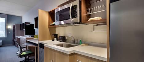 A modern kitchen with a built-in microwave, stainless steel sink, and a refrigerator.