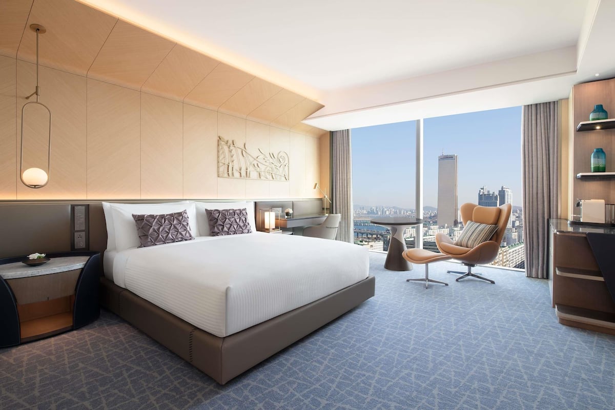 Une chambre d’hôtel moderne avec un grand lit, un bureau, une chaise et une vue sur la ville.