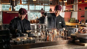Des chefs préparent des plats de fruits de mer dans une cuisine professionnelle équipée d’appareils en acier inoxydable et dotée d’un plan de travail en marbre.