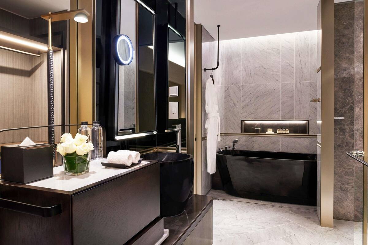 Une salle de bain moderne avec un grand miroir, un meuble-lavabo, une baignoire et un porte-serviettes.