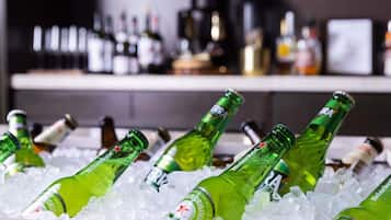 Bottles of Heineken beer in ice, with a bar and various bottles in the background.