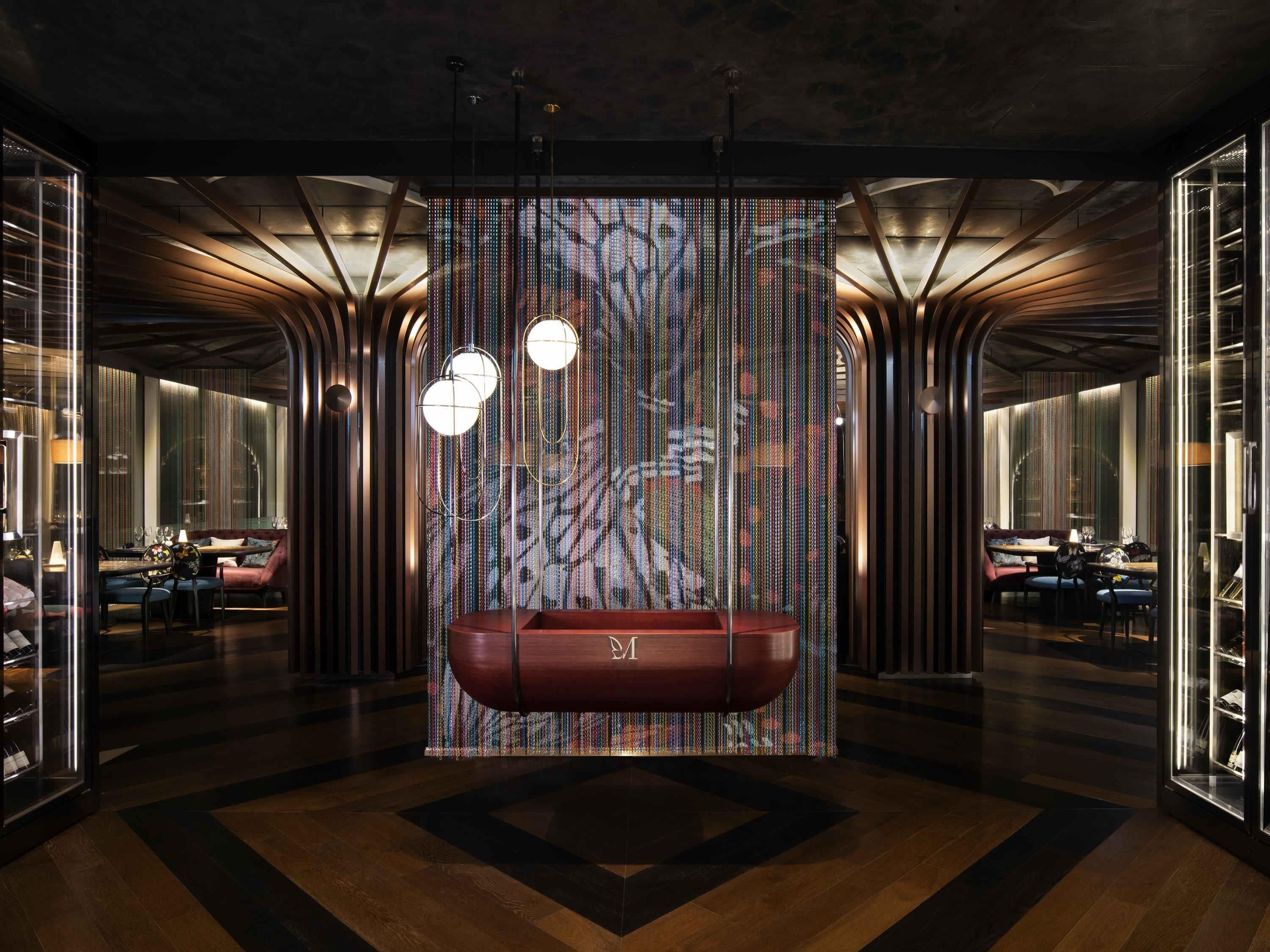 A modern interior with a central seating area, a patterned wall, and a unique lighting fixture.