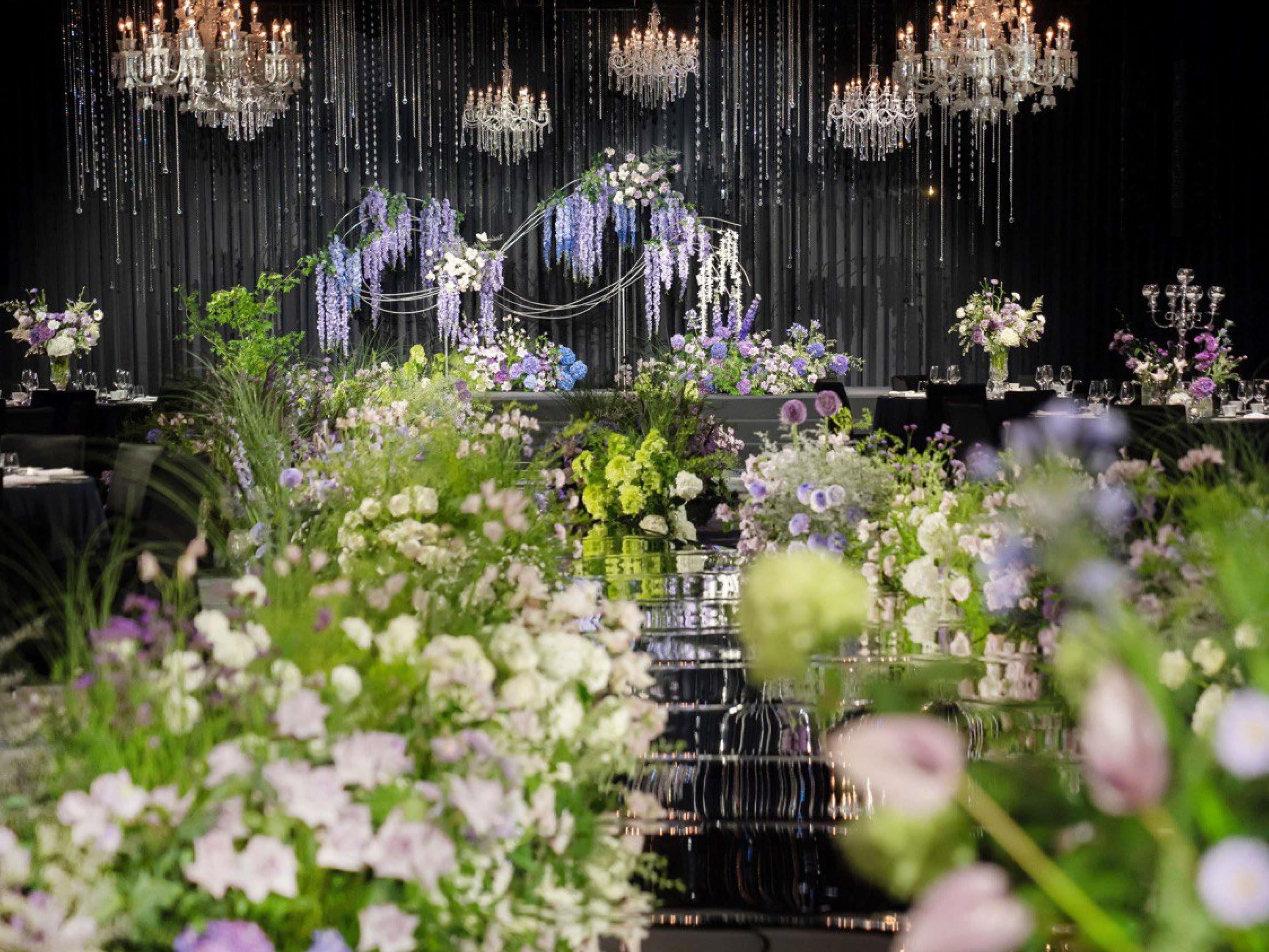 A formal event setting with tables, floral arrangements, and chandeliers.