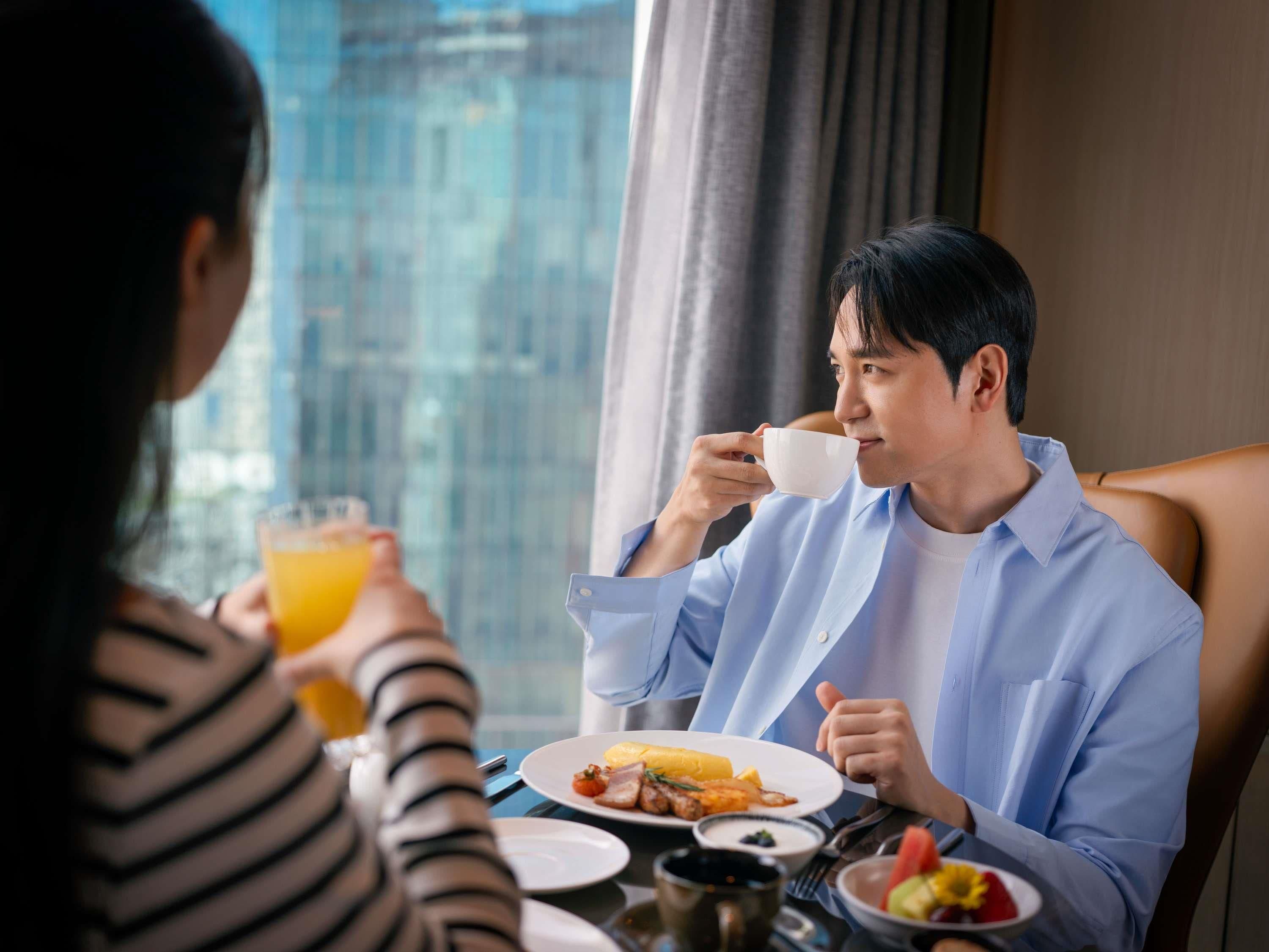 A dining table with plates of food, a cup, and a glass of orange juice.
