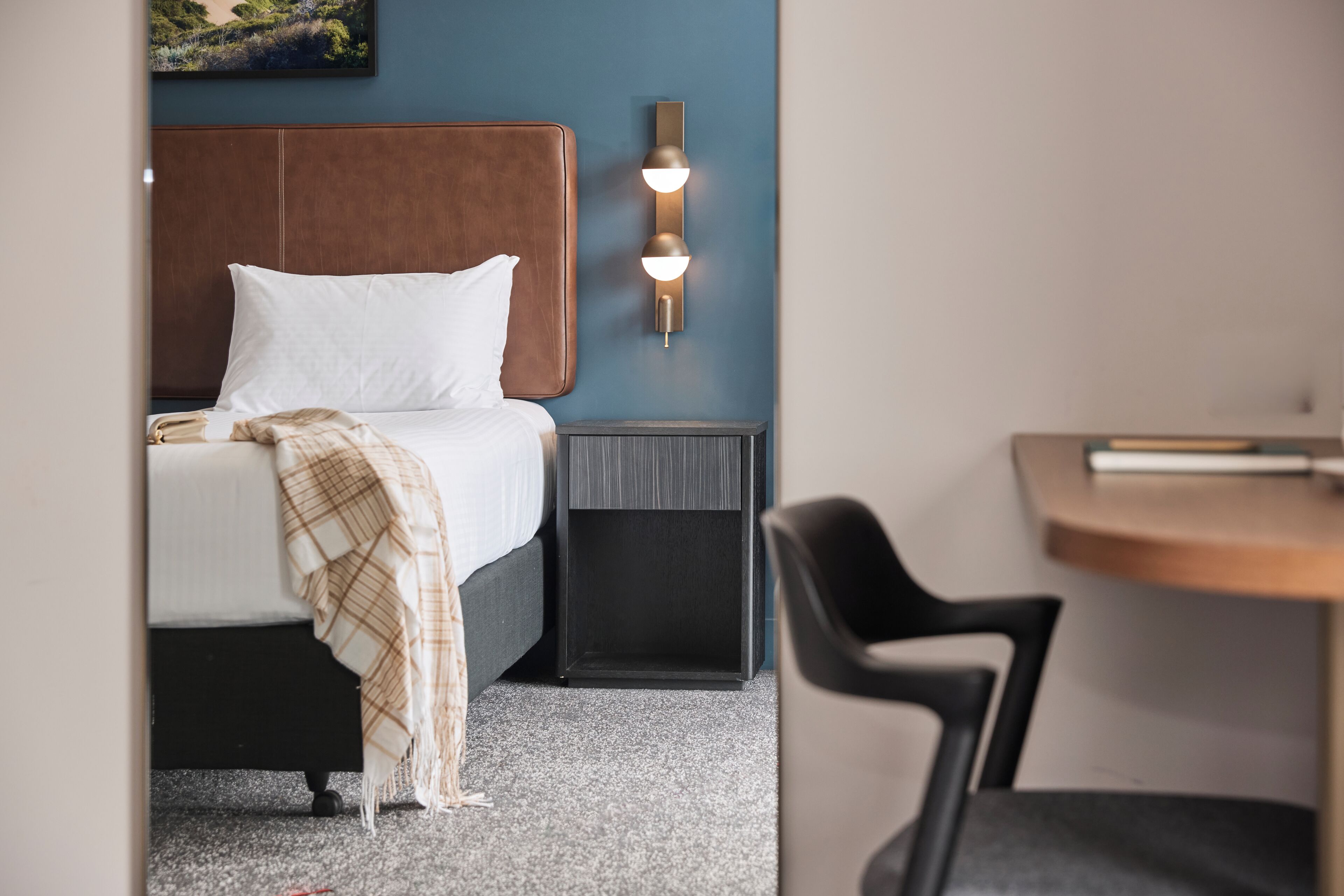 Una camera d'albergo con un letto, un comodino e una sedia.