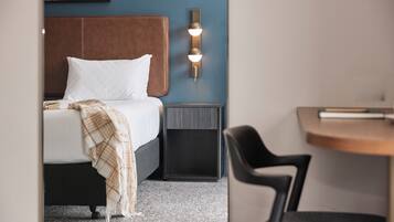 Una camera d'albergo con un letto, un comodino e una sedia.