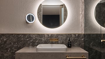 Un baño con un espejo ovalado grande, un lavamanos rectangular y un grifo dorado.