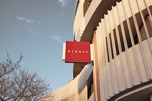 A building with a prominent red sign reading "RYDGES" against a clear sky. - Rydges Ringwood (Ringwood)