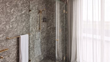 Une salle de bain moderne avec des murs en marbre, une douche en verre et un porte-serviettes.
