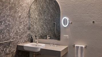A modern bathroom with a marble sink, a large mirror, and a towel rack.