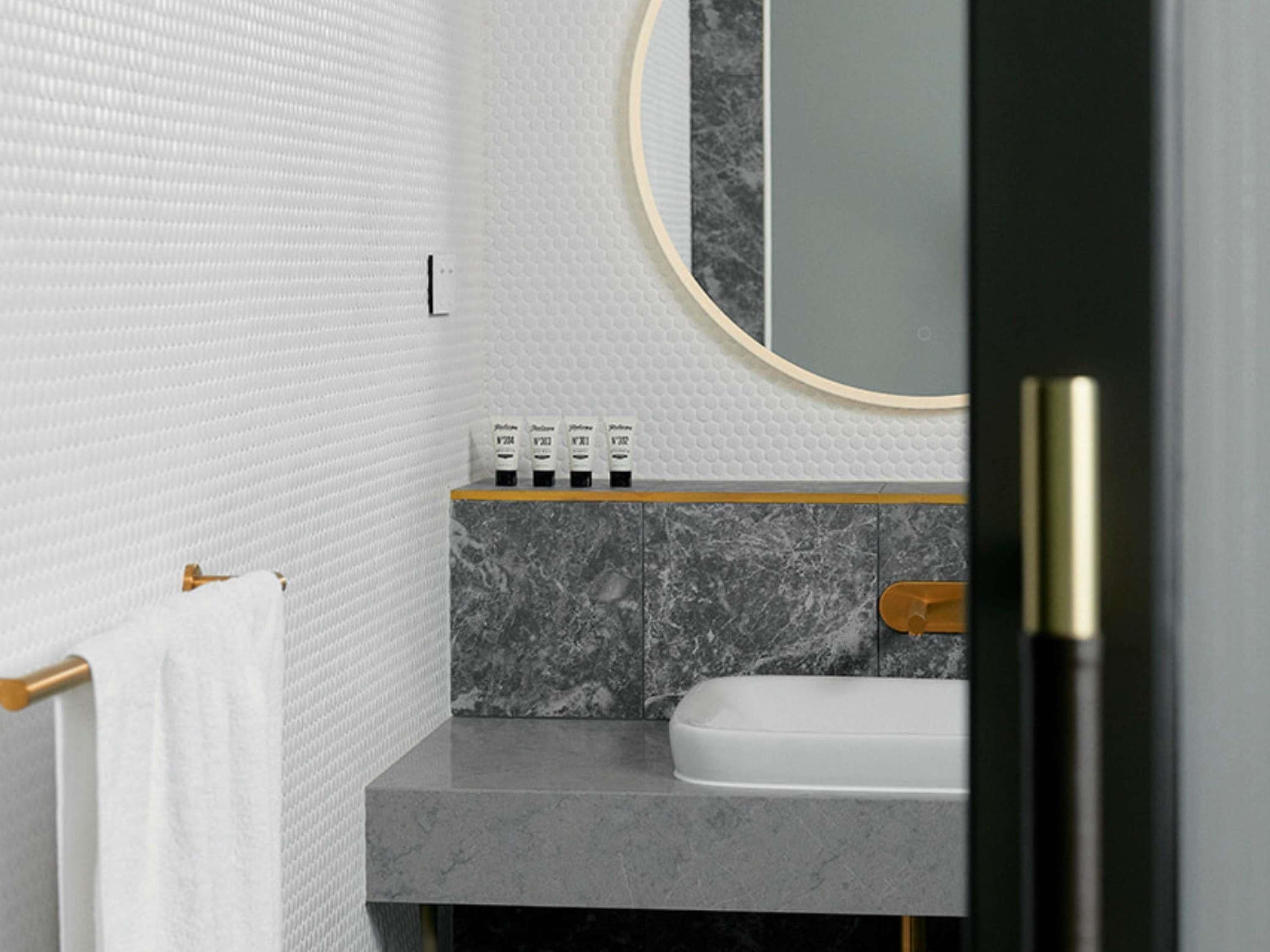 A bathroom with a marble sink, a towel rack, and a mirror with a gold frame.