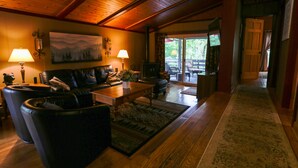 A spacious living room with a wooden ceiling, leather sofas, a coffee table, and a large painting on the wall. - Special…rent 2 nights get the 3rd night…FREE! (Champion)