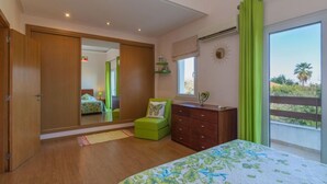 Une chambre à coucher comprenant un lit, une commode, une chaise, une fenêtre donnant sur un beau paysage et un miroir.