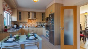 Une cuisine moderne avec des meubles en bois, un réfrigérateur en acier inoxydable et un coin repas avec une table dressée pour deux personnes.