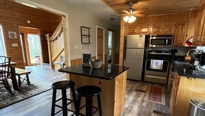 A kitchen with wooden cabinets, a black countertop, a refrigerator, a microwave, and a stove. There are two stools at the kitchen island. - WINDSONG! Peaceful, Quiet Cabin Bordering Nat. Park Near Downtown Gatlinburg (Gatlinburg)