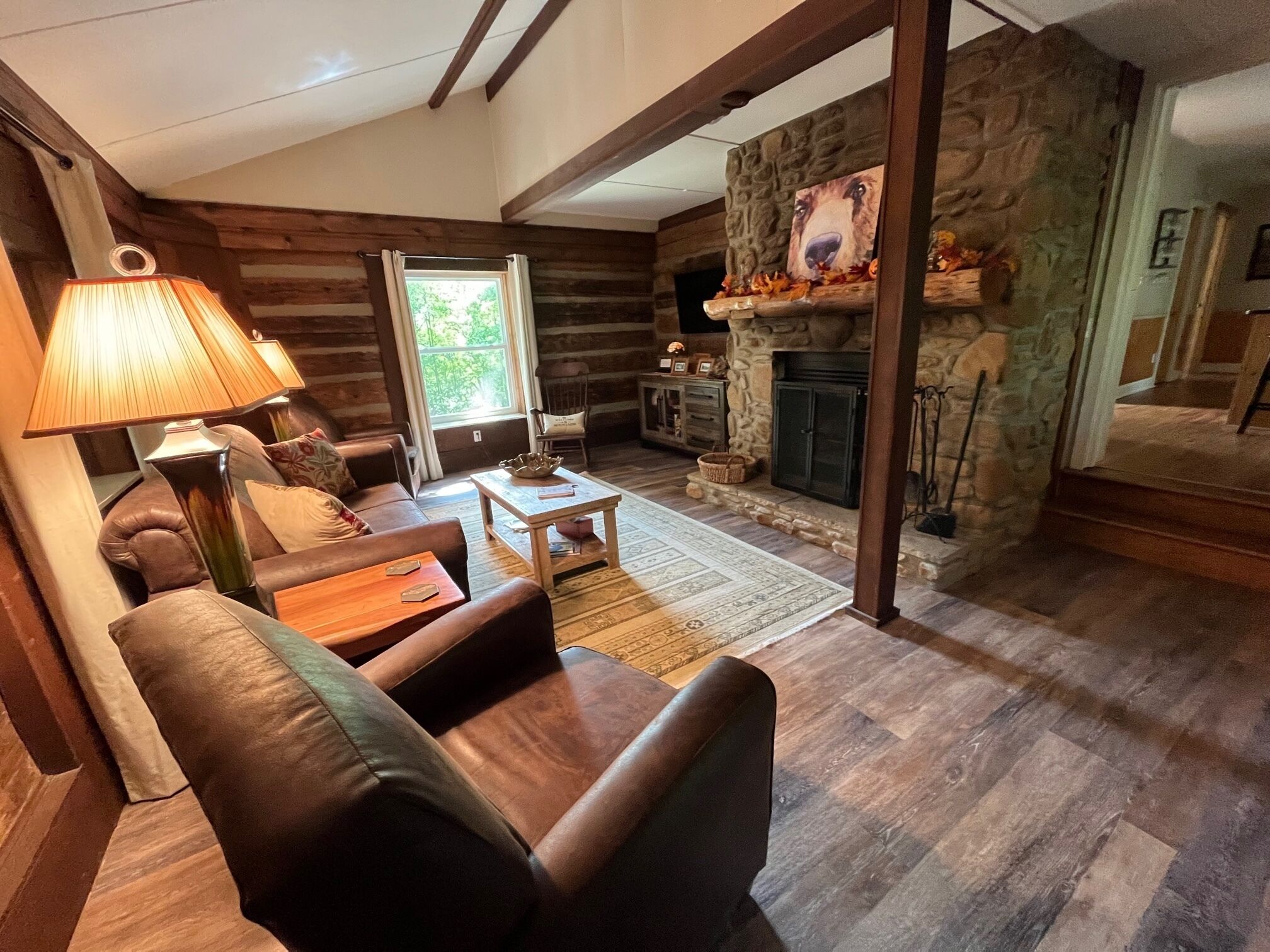 L'intérieur d'une cabane en rondins, avec une cheminée, un canapé en cuir et une lampe.