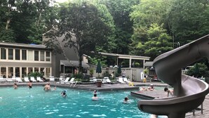 A pool area with lounge chairs, a slide, and a building in the background. - WINDSONG! Peaceful, Quiet Cabin Bordering Nat. Park Near Downtown Gatlinburg (Gatlinburg)