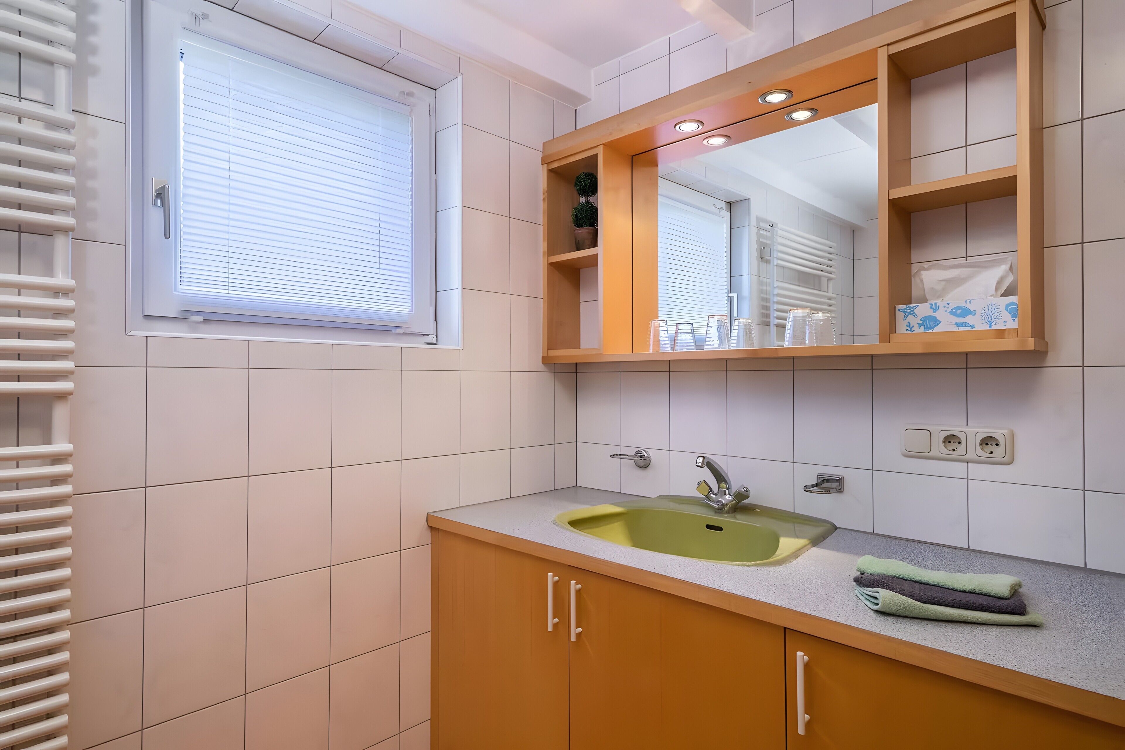 Ein Badezimmer mit Fenster, Waschbecken und Spiegel.